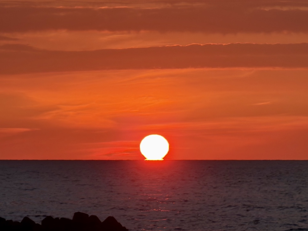 日本海の水平線に接して沈み始めた夕日